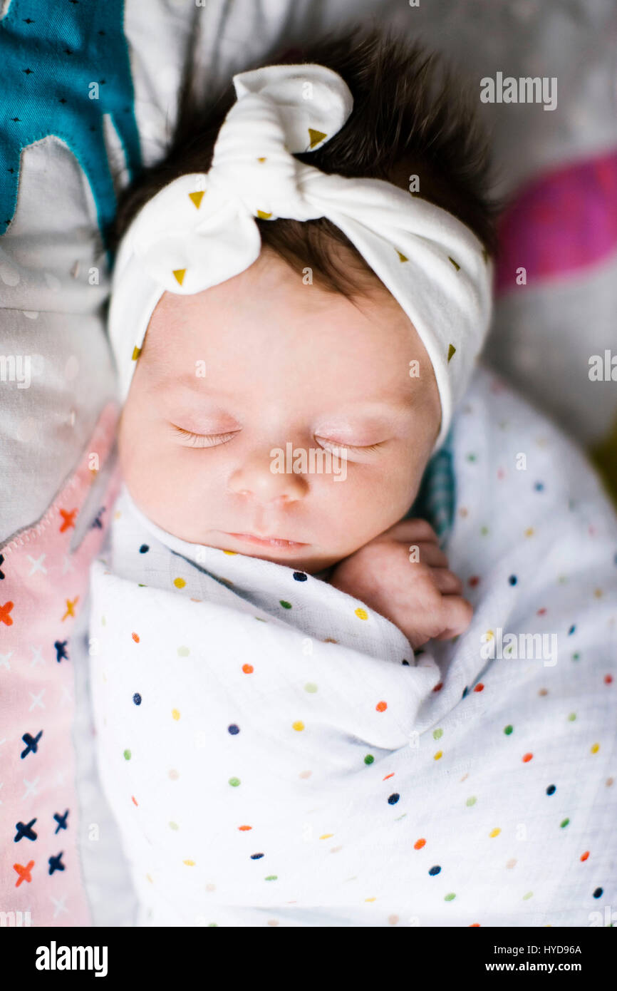 Baby girl (0-1 months) wrapped in blanket sleeping on bed Stock Photo