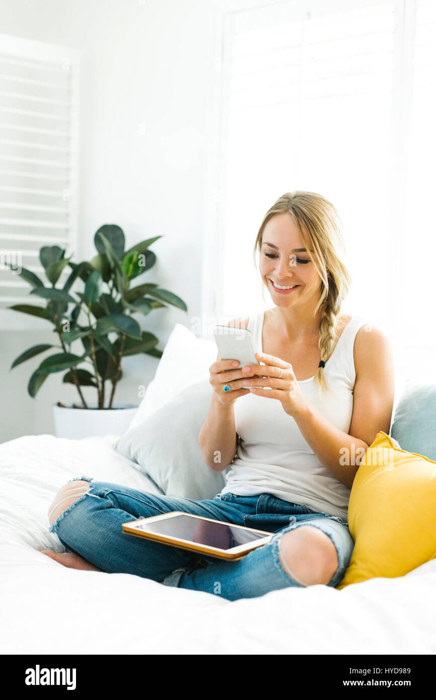 Young woman with mobile phone sitting on sofa Stock Photo - Alamy