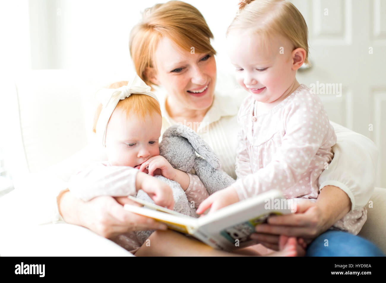 Mother reading book to daughters ( 12-17 months ) Stock Photo