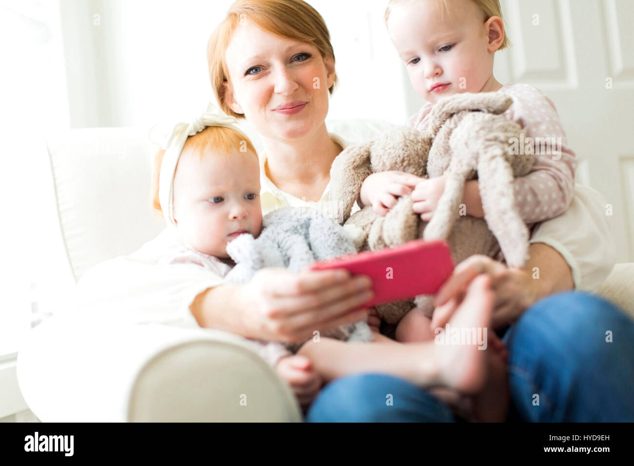Portrait of mother using smart phone with daughters ( 12-17 months ) Stock Photo