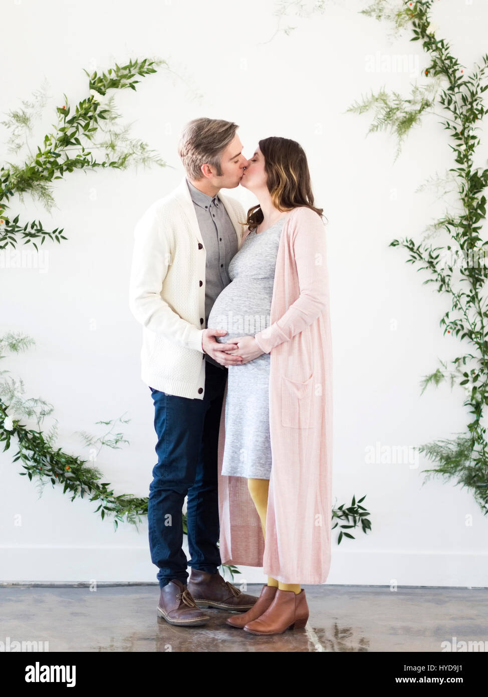 Portrait of men and pregnant woman kissing Stock Photo - Alamy