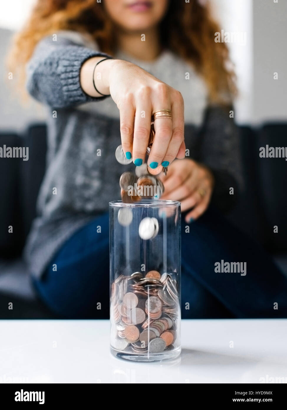 Woman dropping coins into glass container Stock Photo
