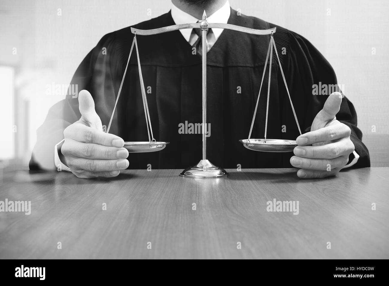 justice and law concept.Male judge in a courtroom with the balance scaleon wood table,black and white Stock Photo