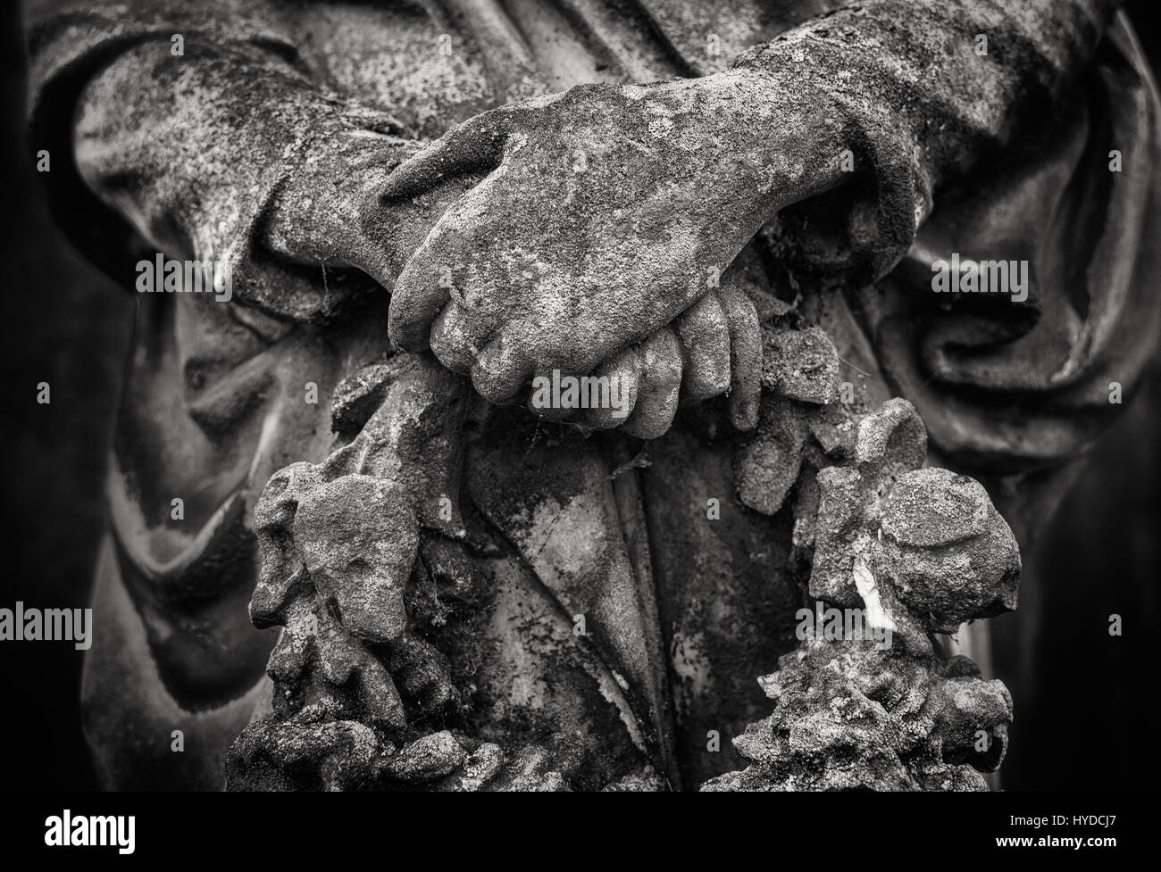 Crossed hands of an angel statue holding a wreath in black and white Stock Photo