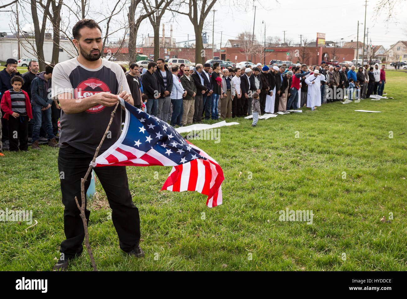Dearborn, Michigan - A man fixes a flag as Muslim men prepare to pray in a park near the American Muslim Society's mosque. The Friday prayers came at  Stock Photo