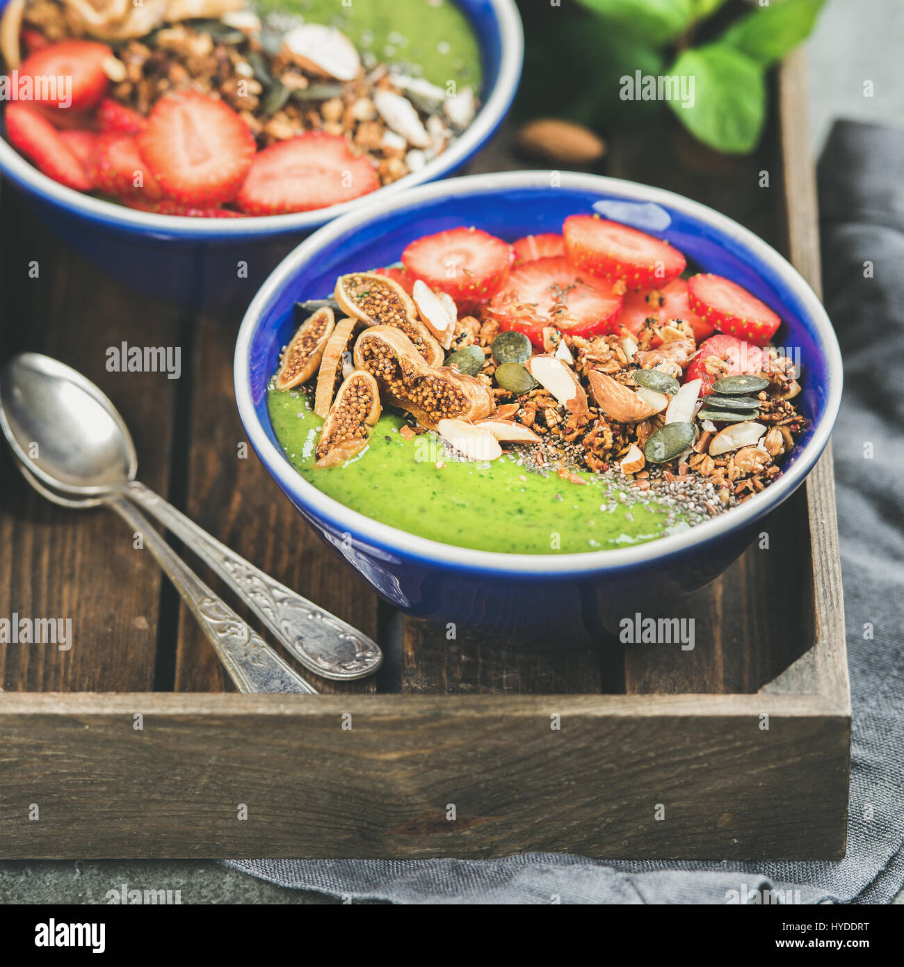 Green smoothie bowls with seeds, nuts and fruit, square crop Stock
