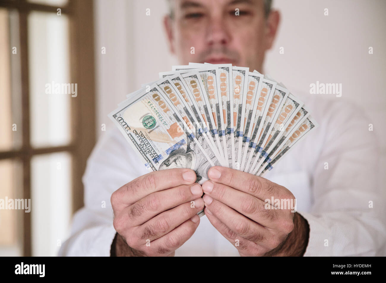 A man fans out two hands full of new one hundred dollar bills in US currency Stock Photo