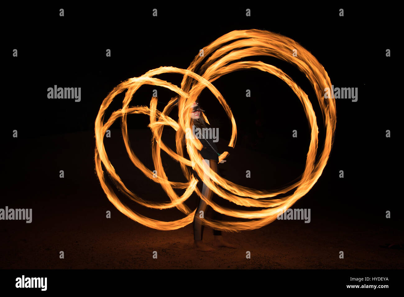 Street artist dancing with flaming fire pois after night fall. Dubai, United Arab Emirates. Stock Photo