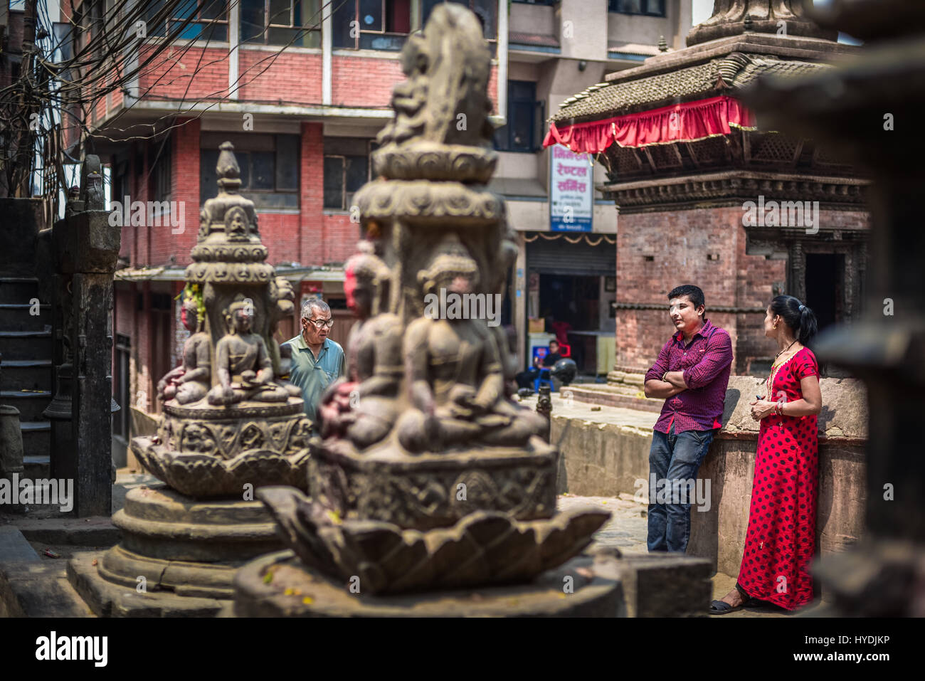 Local people having leisure time near Hindu sculptures at the residential neighborhood of Kathmandu, Nepal. Stock Photo