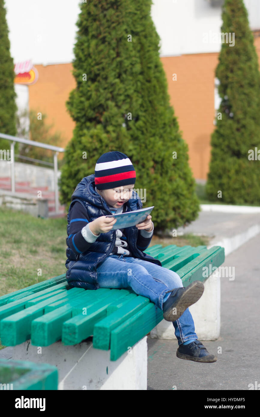 the little boy took seat on a bench in park and reads the book Stock ...