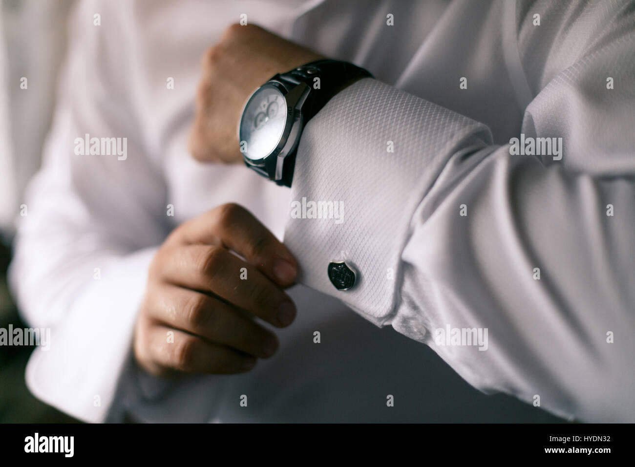 man in white shirt buttons on the hand cuffs to the clock Stock Photo
