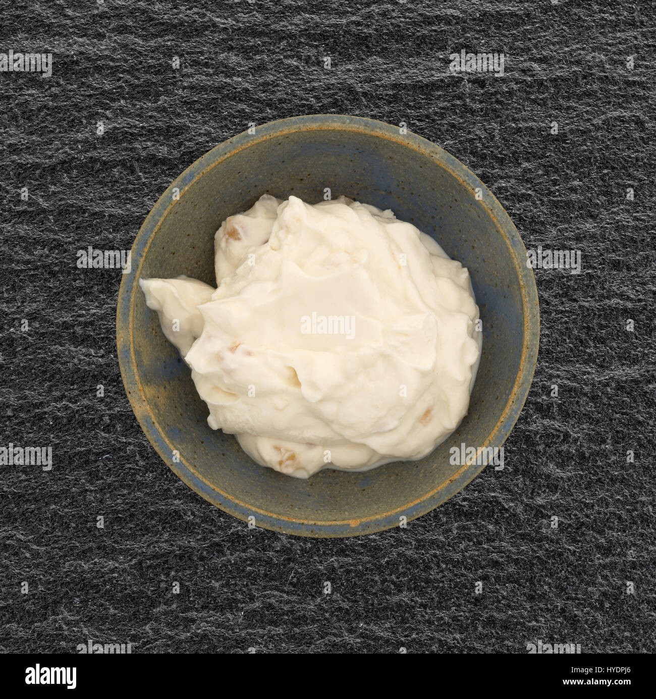 Top view of a serving of apple vanilla Greek yogurt in an old stoneware bowl atop a black slate table. Stock Photo