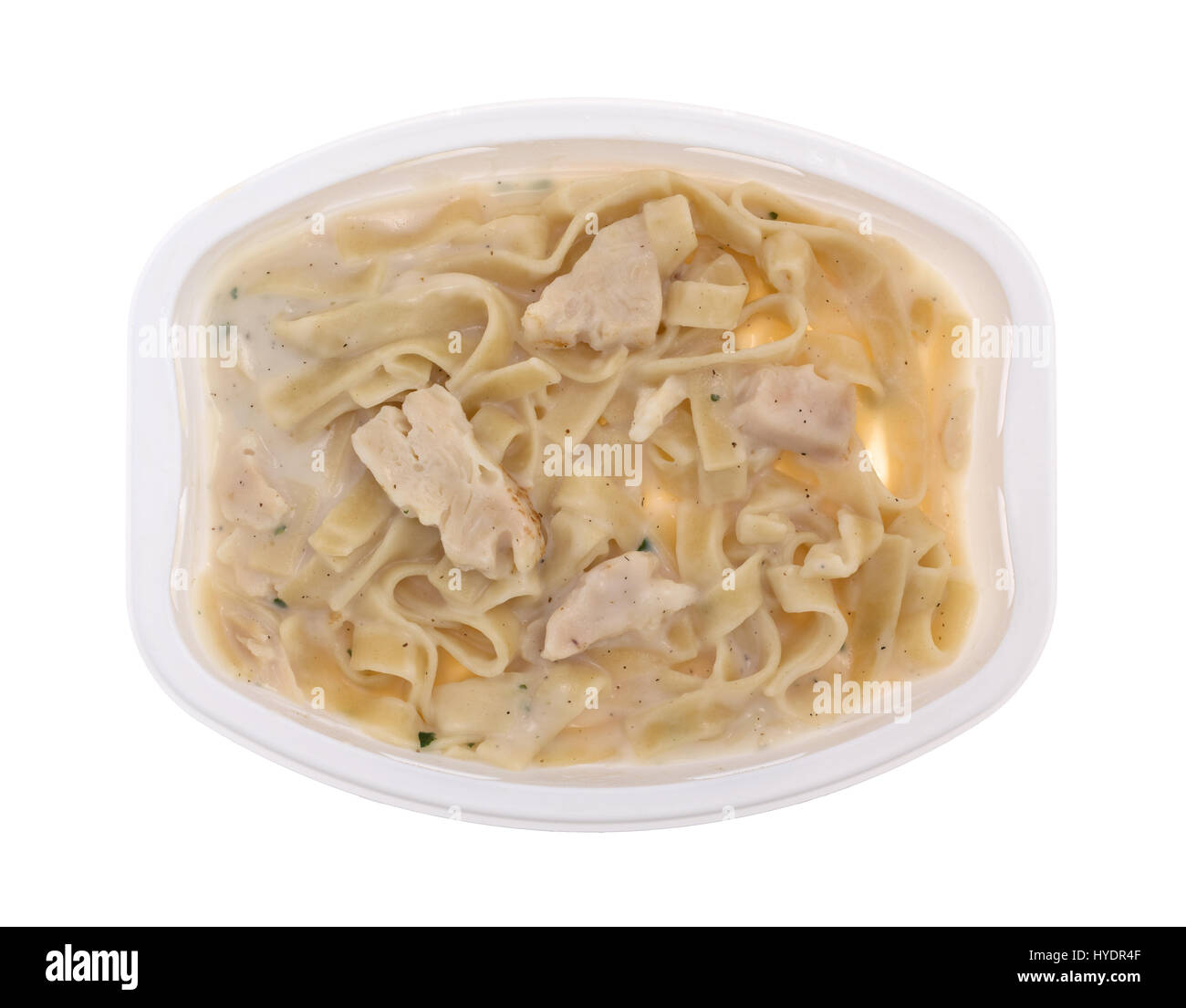 Top view of a cooked TV dinner of fettuccini with chicken and seasonings in a plastic tray isolated on a white background. Stock Photo