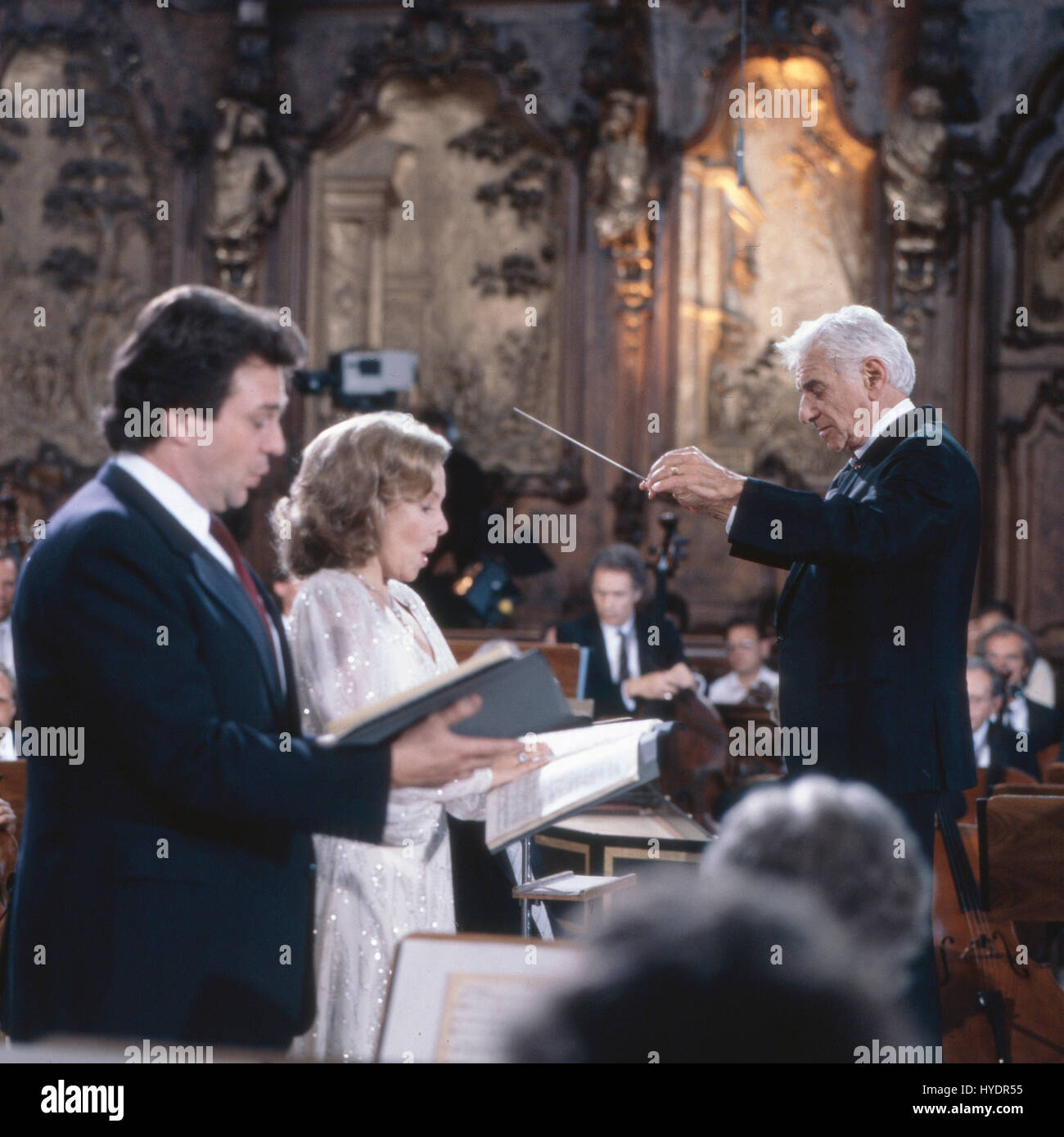 Amerikanischer Pianist, Komponist und Dirigent Leonard Bernstein dirigiert in der Basilika Ottobeuren das Haydn Oratorium 'Die Schöpfung' Tenor Thomas Moser und Sopranistin Lucia Popp singen, Deutschland 1980er Jahre. American pianist, composer and conductor Leonard Bernstein performing 'The Creation' by Haydn at Ottobeuren basilica together with tenor Thomas Moser and soprano Lucia Popp, Germany 1980s. Stock Photo