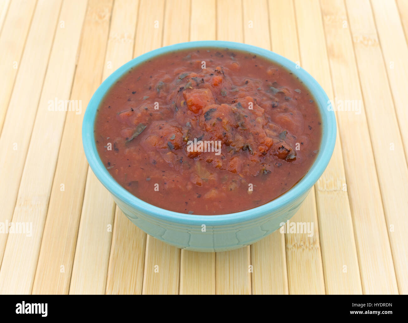 A bowl filled with fire roasted crushed tomatoes on a wood place mat