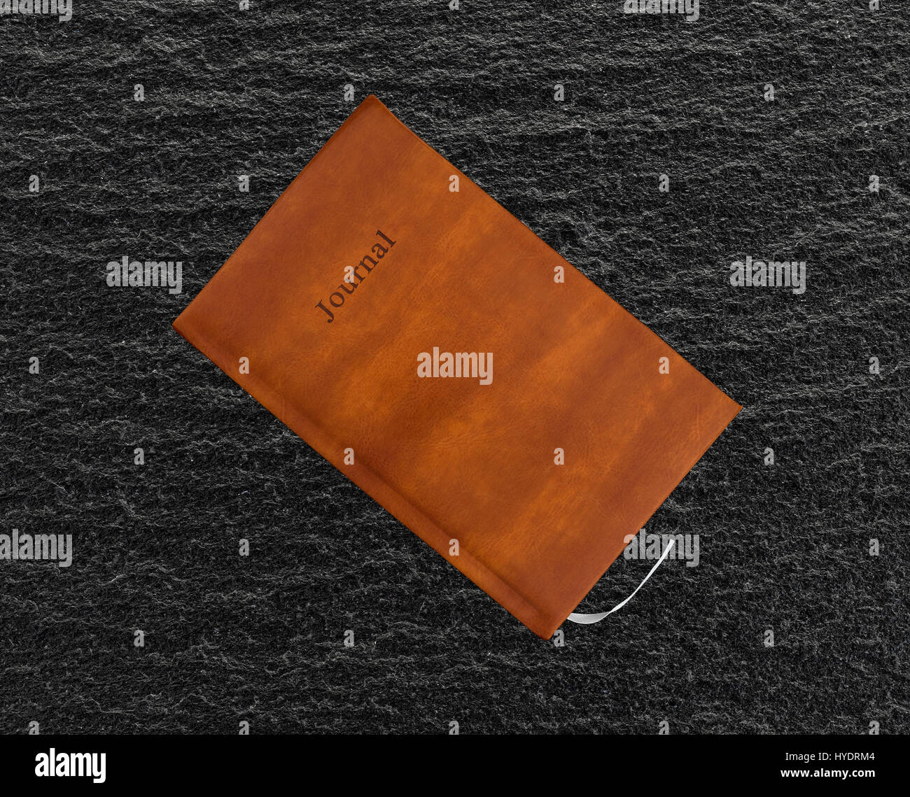 Top view of a brown leather journal on a black slate table. Stock Photo