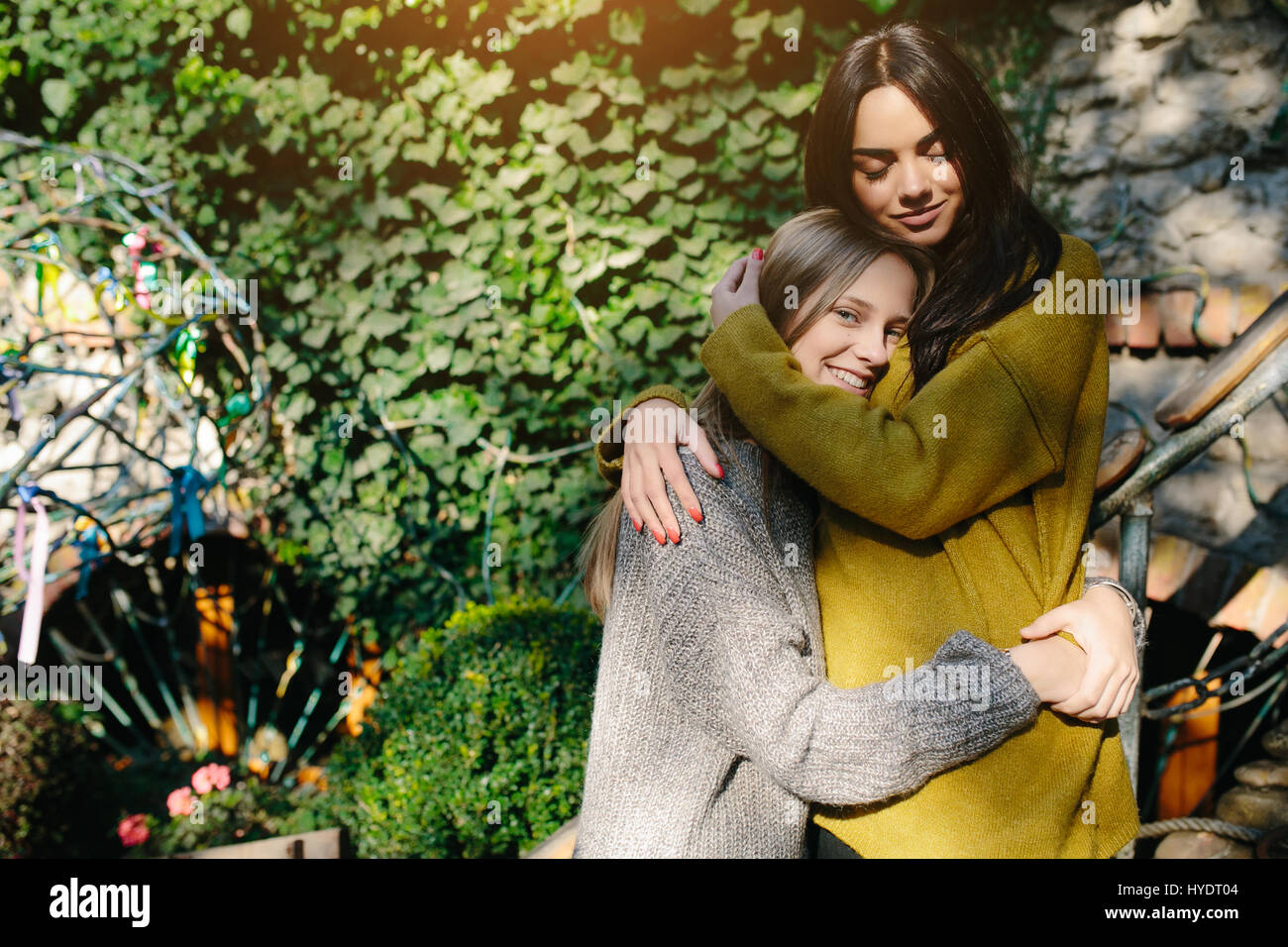 Two girls hugging in the shade of of leaves Stock Photo - Alamy