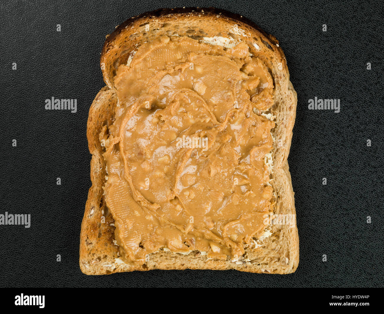Crunchy Peanut Butter Spread on Toast Against a Black Background Stock