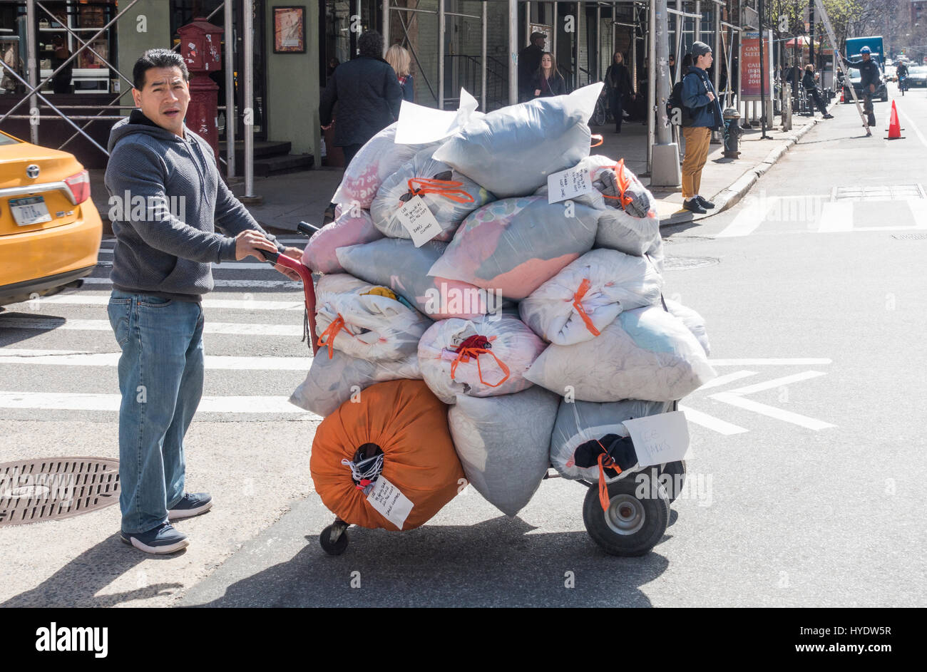 Young man with cart delivering large bundles of laundry Stock Photo - Alamy