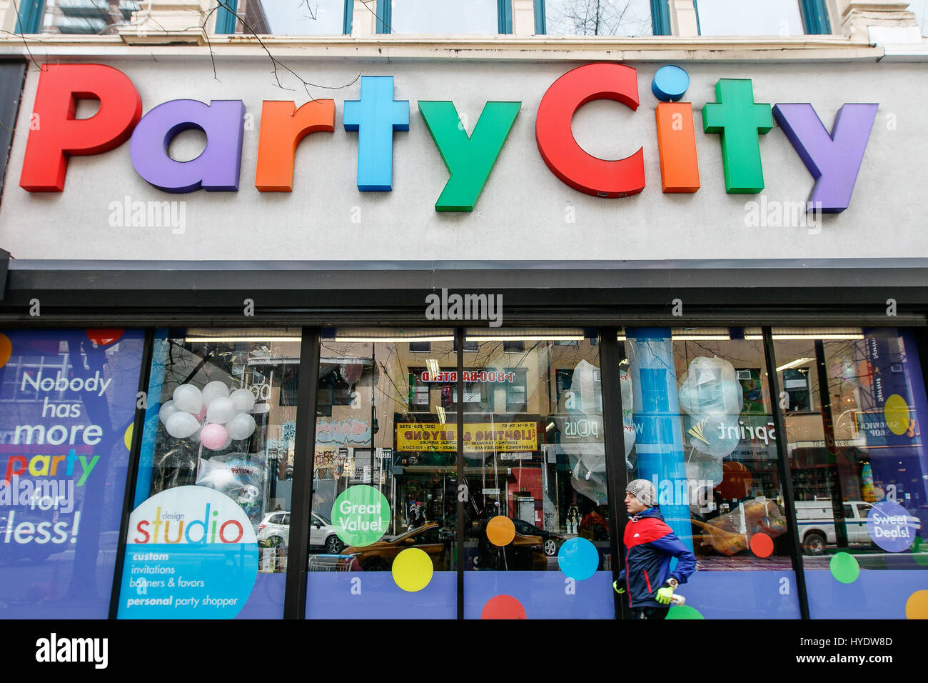 A man is running by a Party City store in Manhattan. Stock Photo
