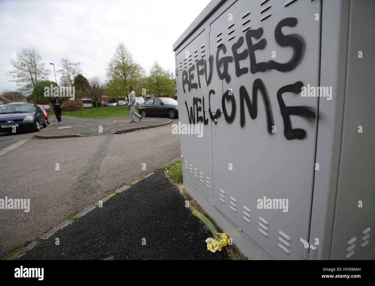 Flowers placed next to grafiti reading 'Refugees Welcome' near to the scene where teenage asylum seeker Kurdish Iranian Reker Ahmed was left fighting for his life after a suspected hate attack in Croydon, south London. Stock Photo