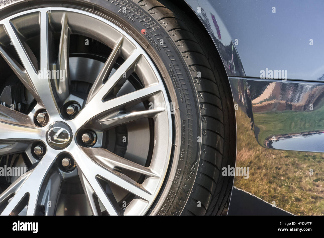 Laverstoke, Hampshire, UK - August 25, 2016: Closeup of a luxury Lexus automobile wheel and tire with sky and grassland reflections in the background Stock Photo