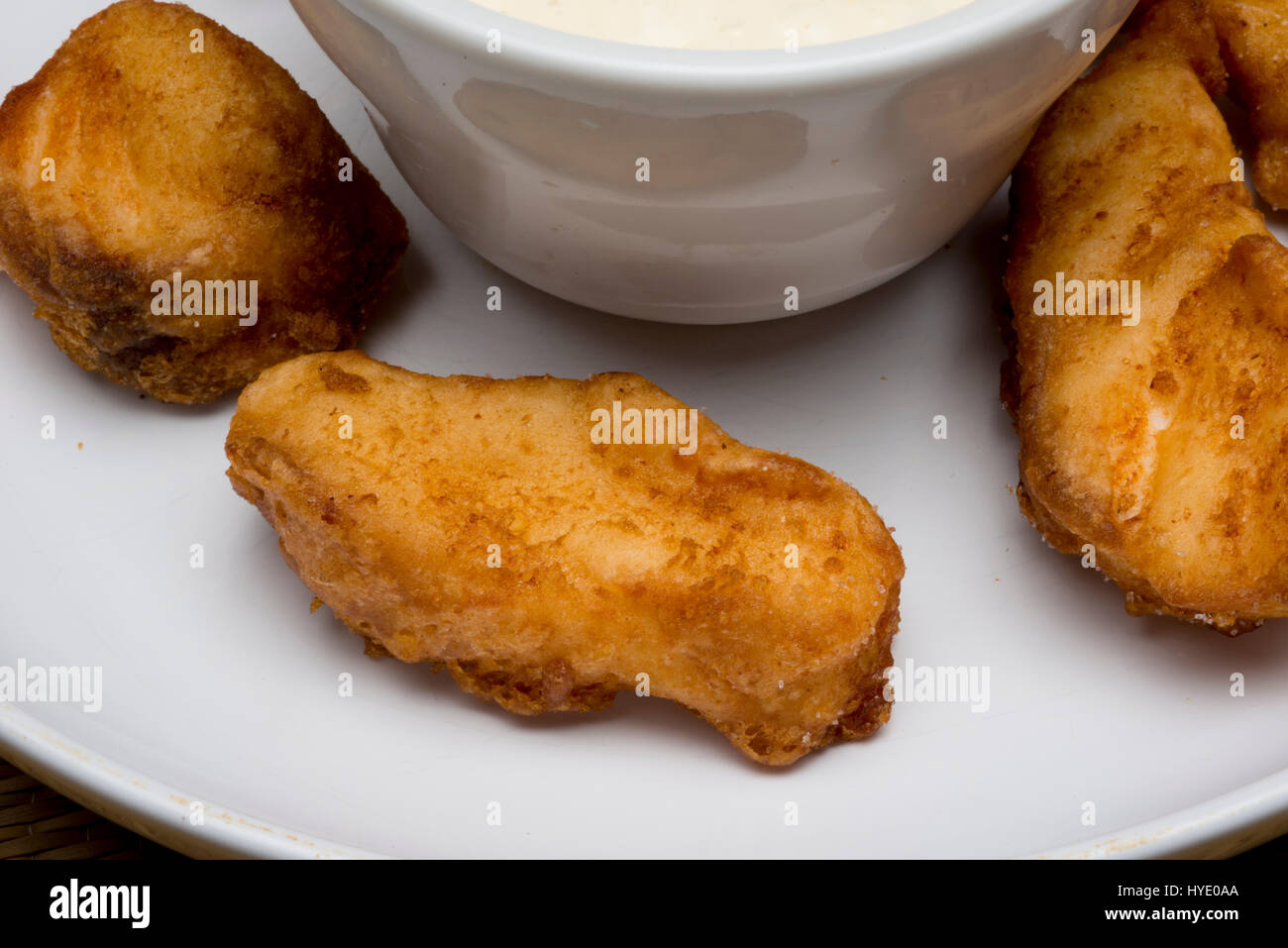 deep fried grouper fingers on white plate with dipping sauce close up