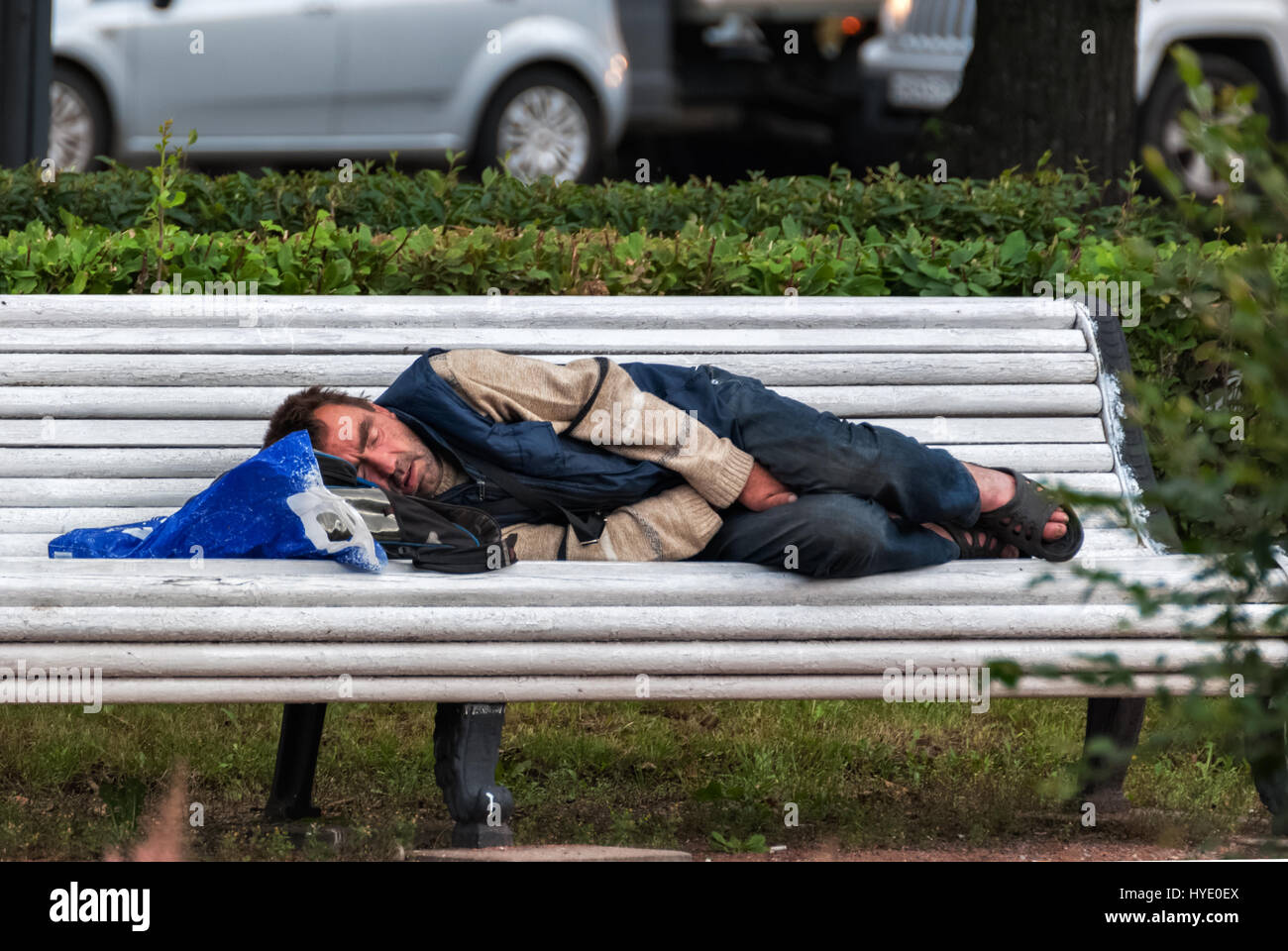 SAINT PETERSBURG, RUSSIA, may 15: A homeless man sleeping on a bench in the town square, in the morning may 15, 2016. Stock Photo