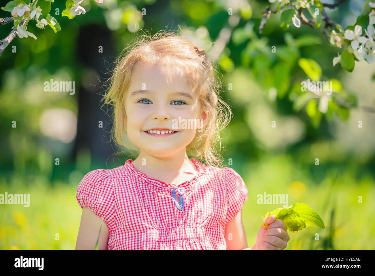 Happy little girl in apple tree garden Stock Photo - Alamy