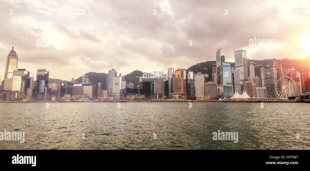 Wide-angle panorama of Hong Kong's Central District skyline on Victoria Harbor at sunset. Viewed from downtown Tsim Sha Tsui on Hong Kong Island. HDR  Stock Photo