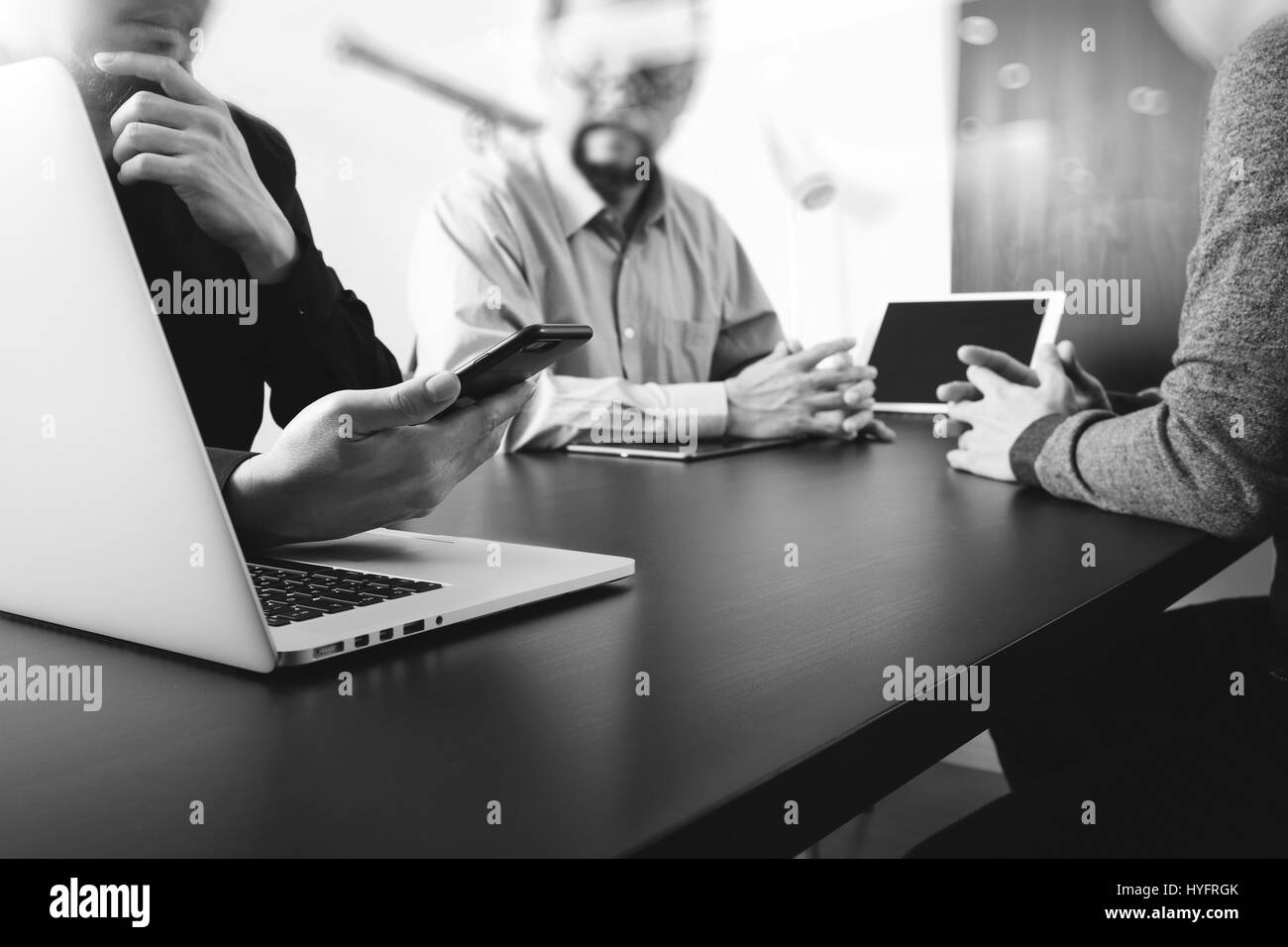 co working team meeting concept,businessman using smart phone and digital tablet and laptop computer in modern office,black and white Stock Photo