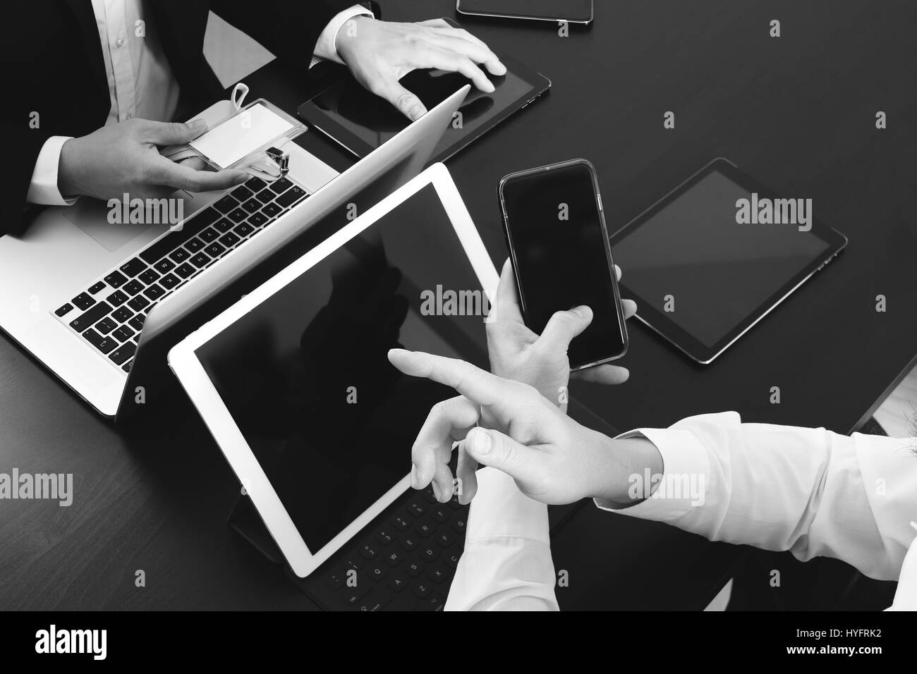 co working team meeting concept,businessman using smart phone and digital tablet and laptop computer and name tag in modern office,black and white Stock Photo