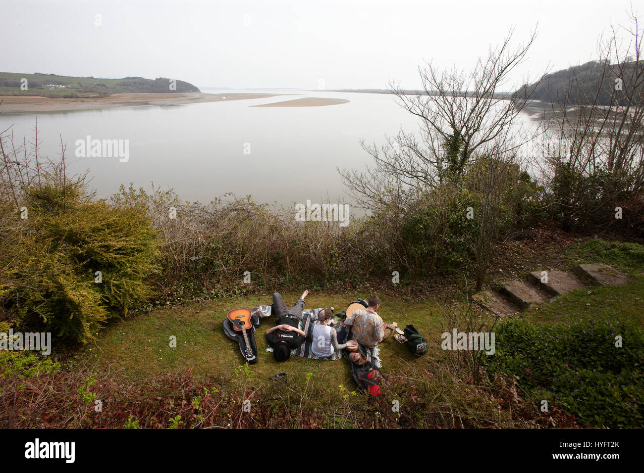 People Relaxing on the grass by the ocean, playing guitar. The Literary Festival, Laugharne, Wales, Uk Stock Photo