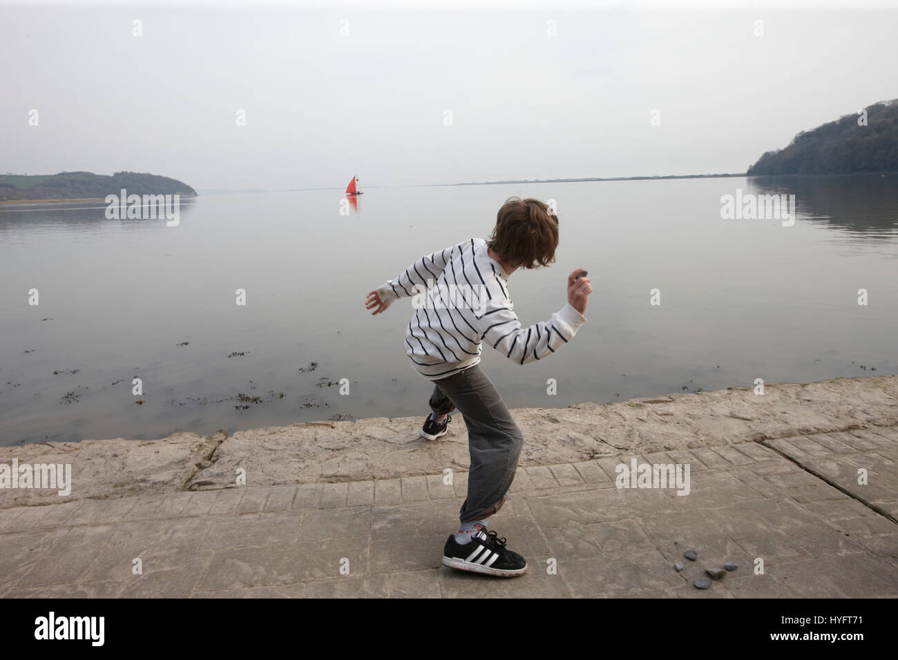Young Boy skipping stones in the ocean at the beach, The Literary