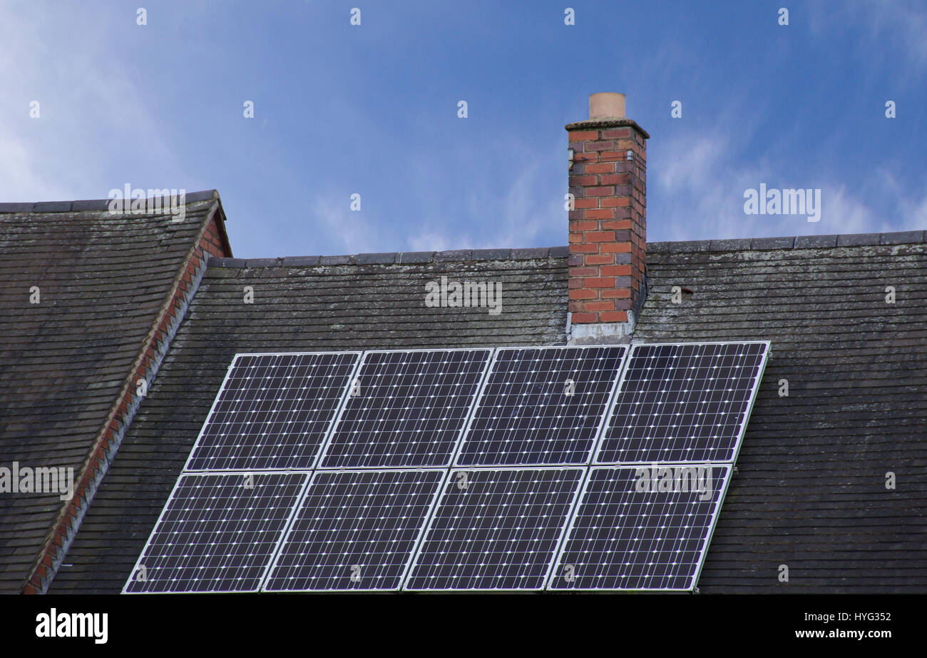 Solar panels on sloped roof top covered with roof tiles with blue sky in background in Stoke on Trent,Staffordshire,UK.Solar cells good weather. Stock Photo