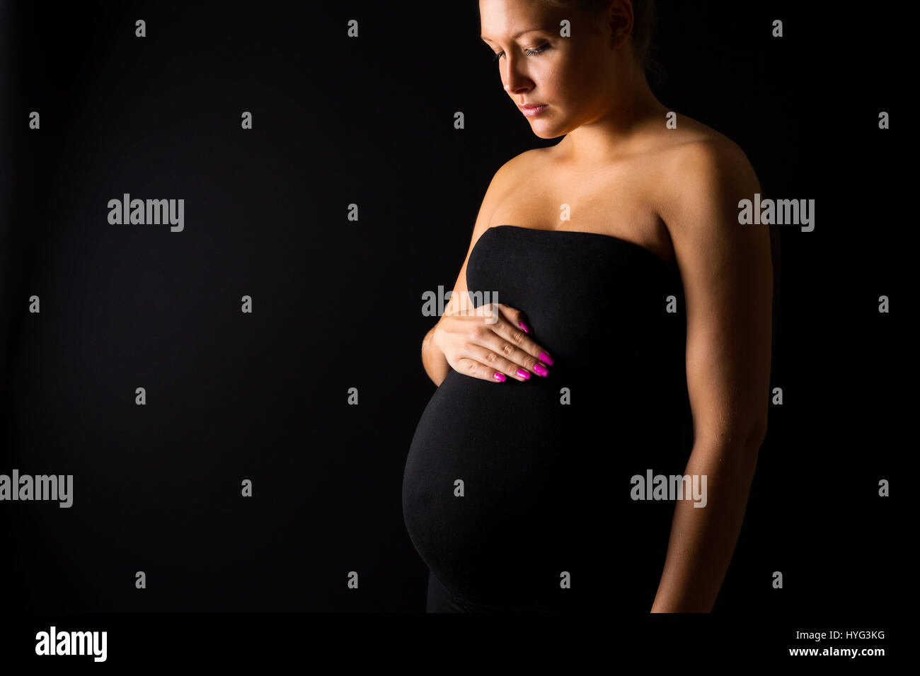 Thoughtful pregnant woman stand with hands at the belly Stock Photo Alamy