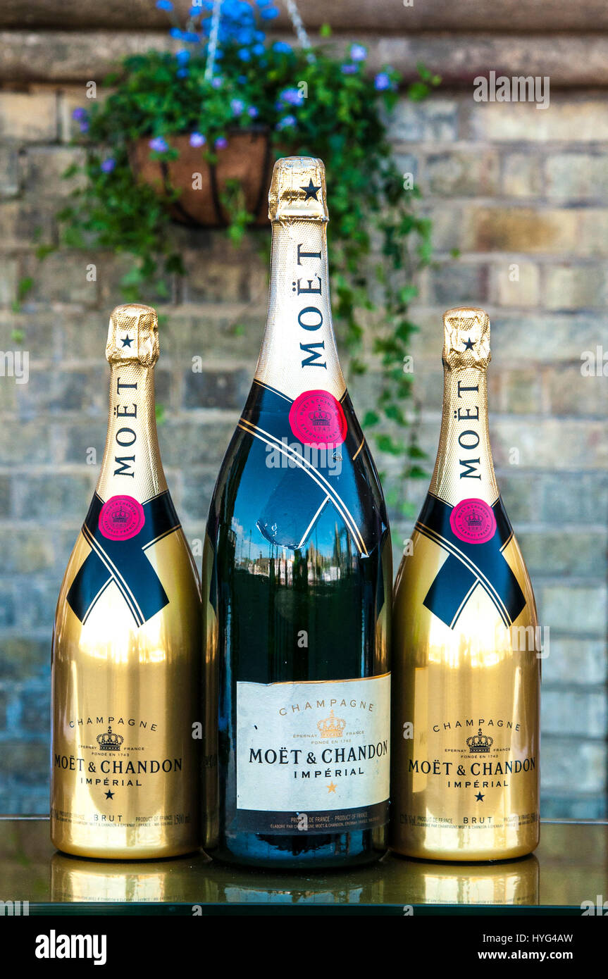 Two gold bottles of Moet & Chandon champagne flank a large green bottle of Moet & Chandon champagne. Stock Photo