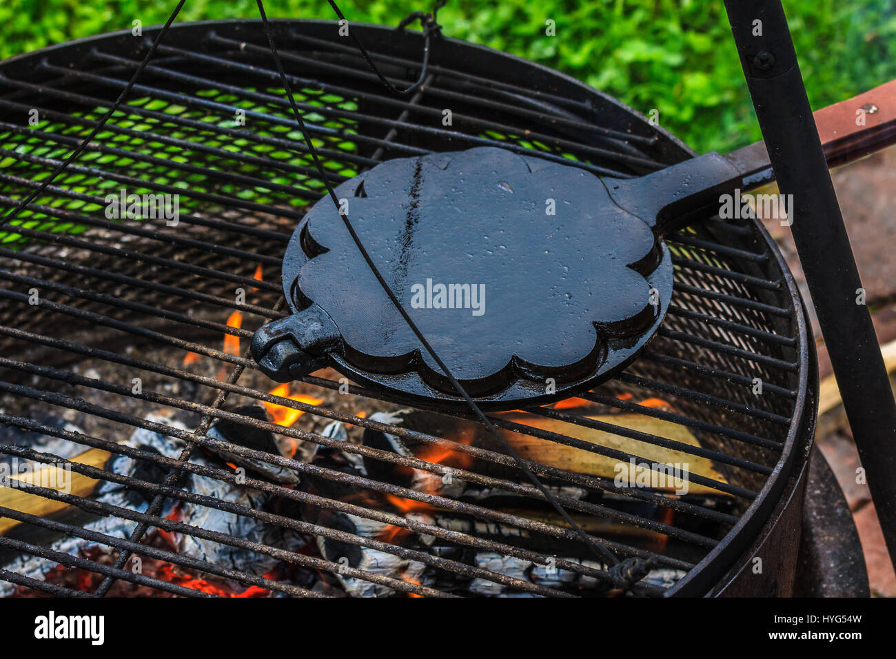Old castiron waffle iron, baking waffles on open flame grill outdoors