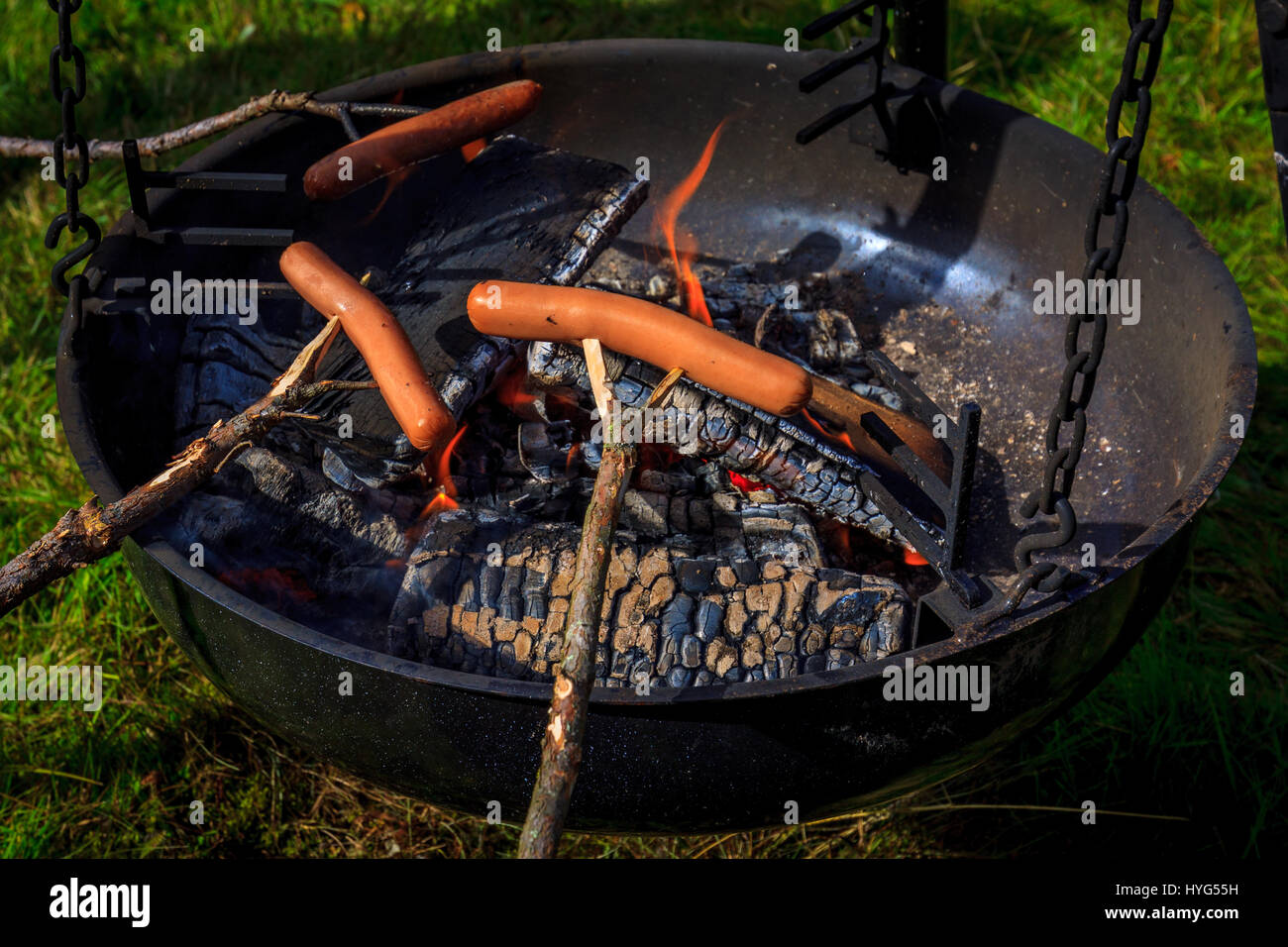 Sausages on sticks, being grilled on open flame Stock Photo Alamy