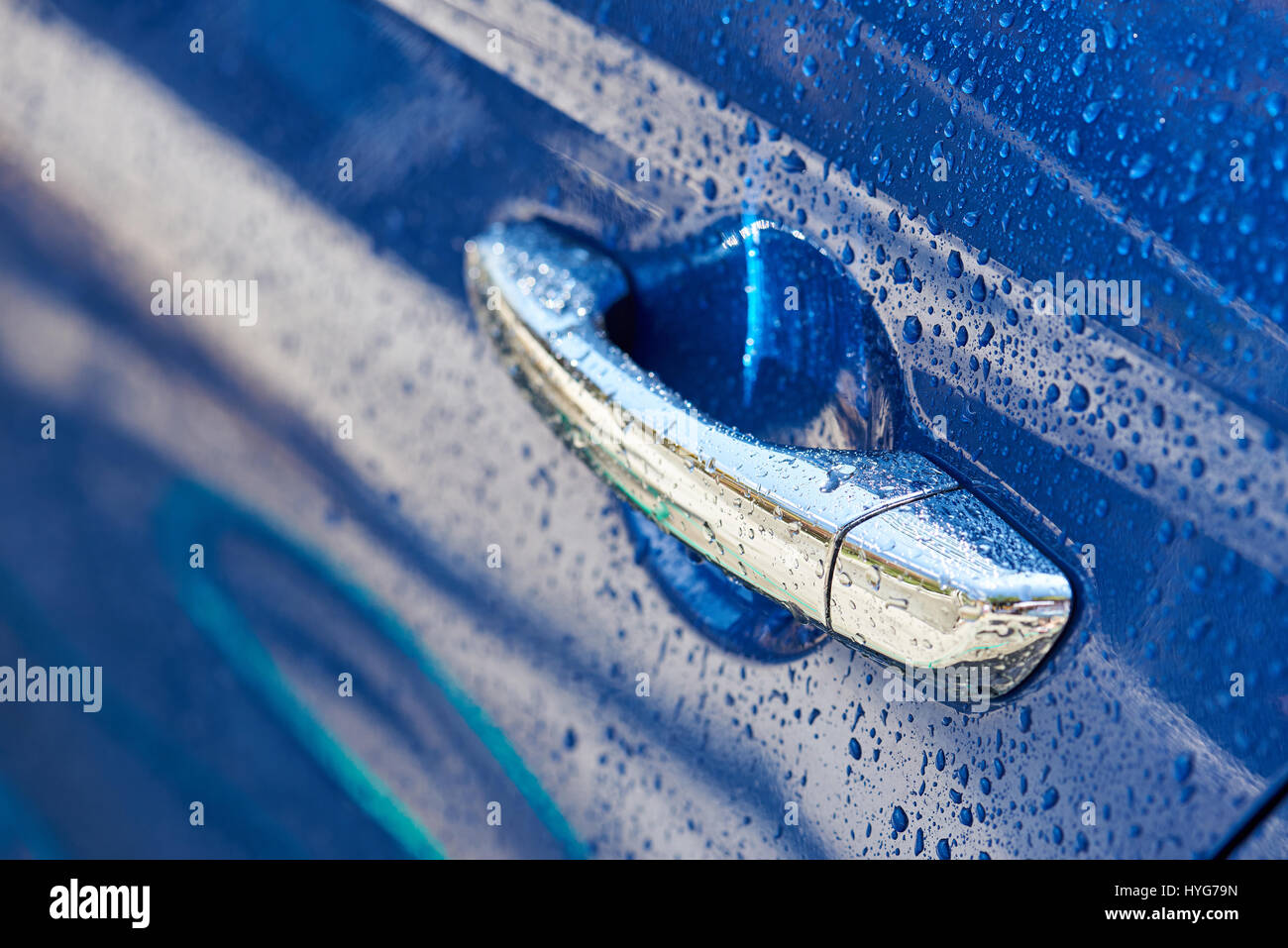 Chrome wet car handle close-up. Rain drops on blue car door Stock Photo