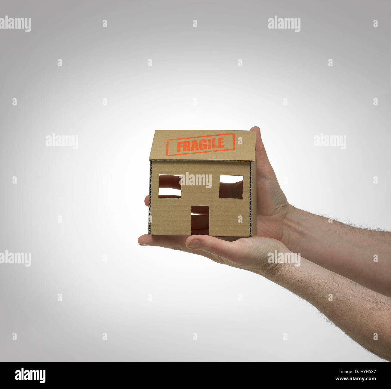 Cardboard House held in hands with fragile stamp. Stock Photo