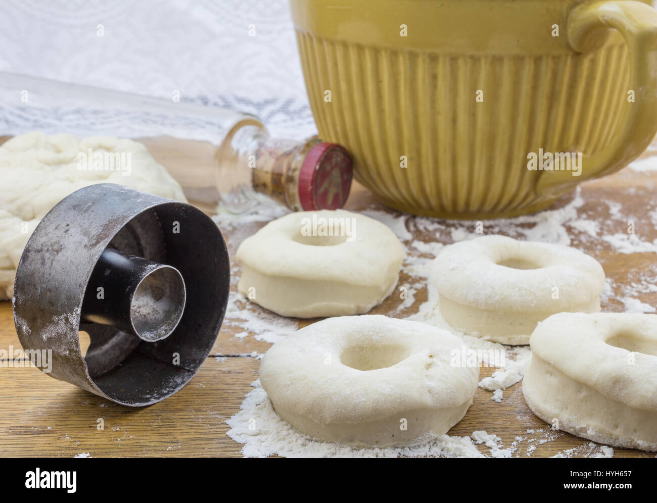 Close up photo of fresh donuts rolled out on floured wooden kitchen table and round donut cutter Stock Photo