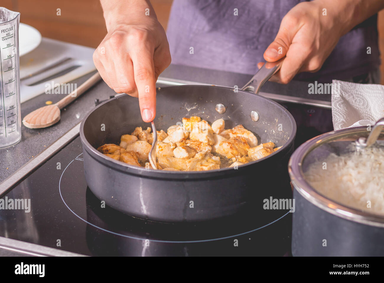 Cook frying chicken in a pan of oil on induction plates Stock Photo Alamy