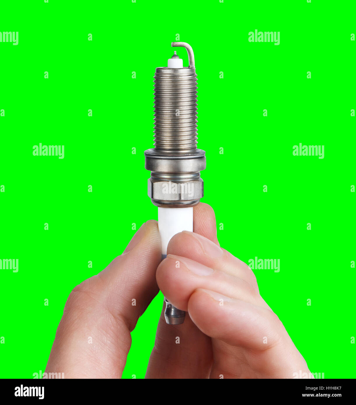 Mechanic holds a spare part spark plug in his hand. Auto part spark plug close-up on a green screen background. Stock Photo