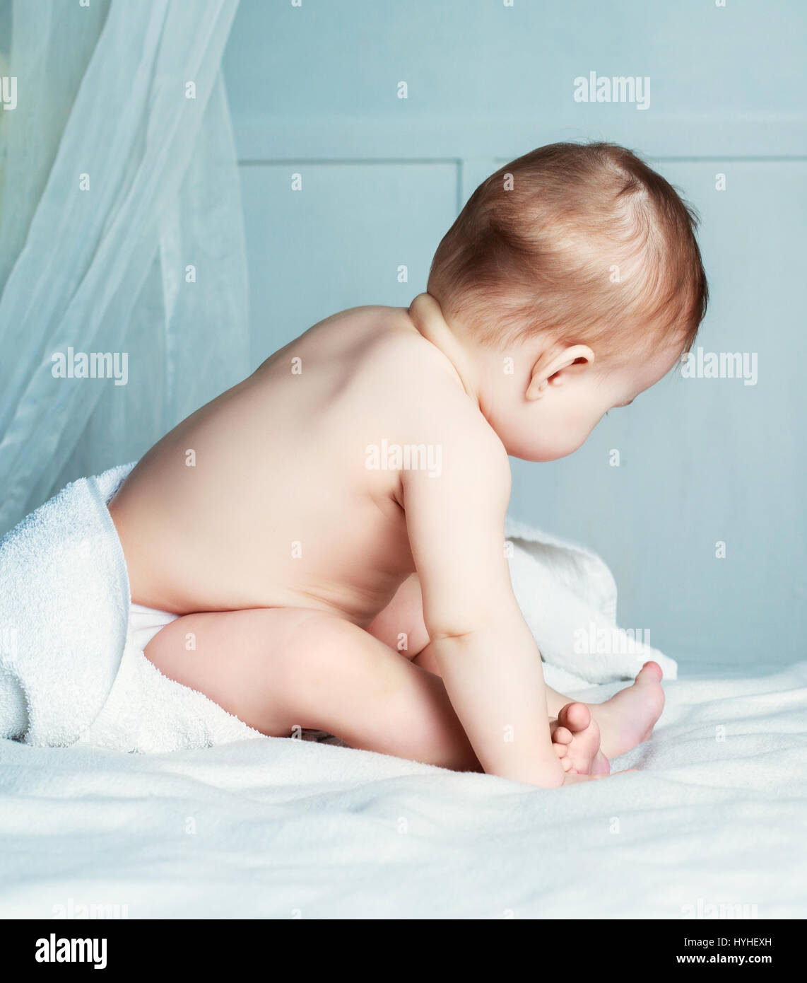 six months old baby with a towel after taking a bath, in bed at home