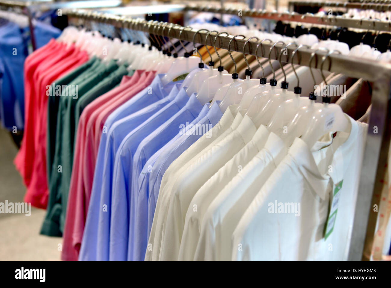 Clothes collection in hangers for sale photo in indoor low lighting. Stock Photo