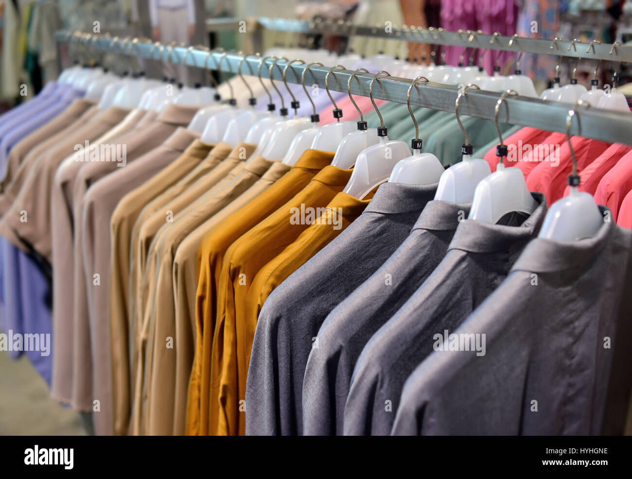 Clothes collection in hangers for sale photo in indoor low lighting. Stock Photo