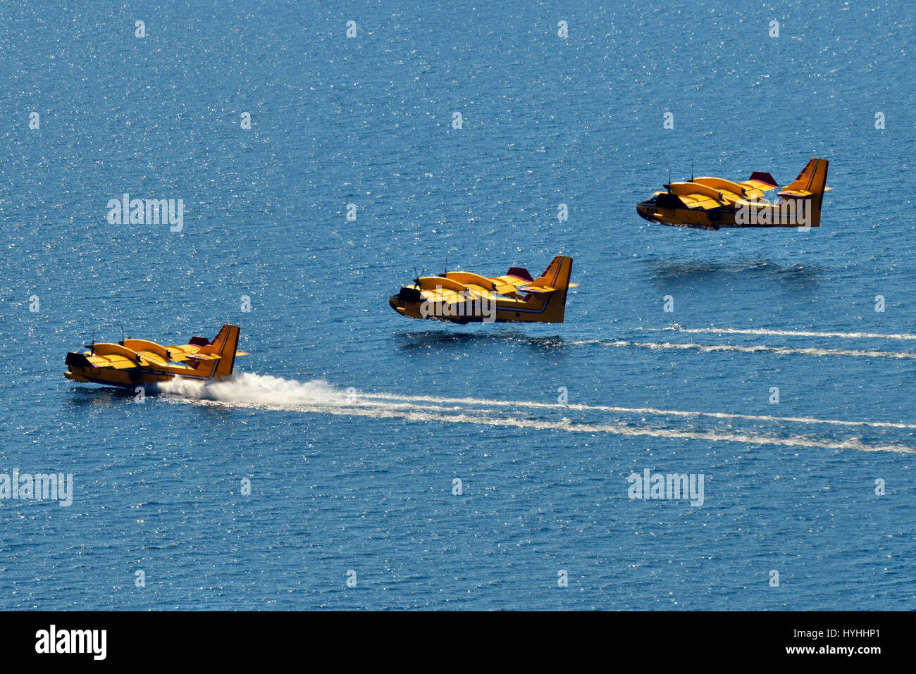 Composite of three aerial water bomber seaplanes landing on the water