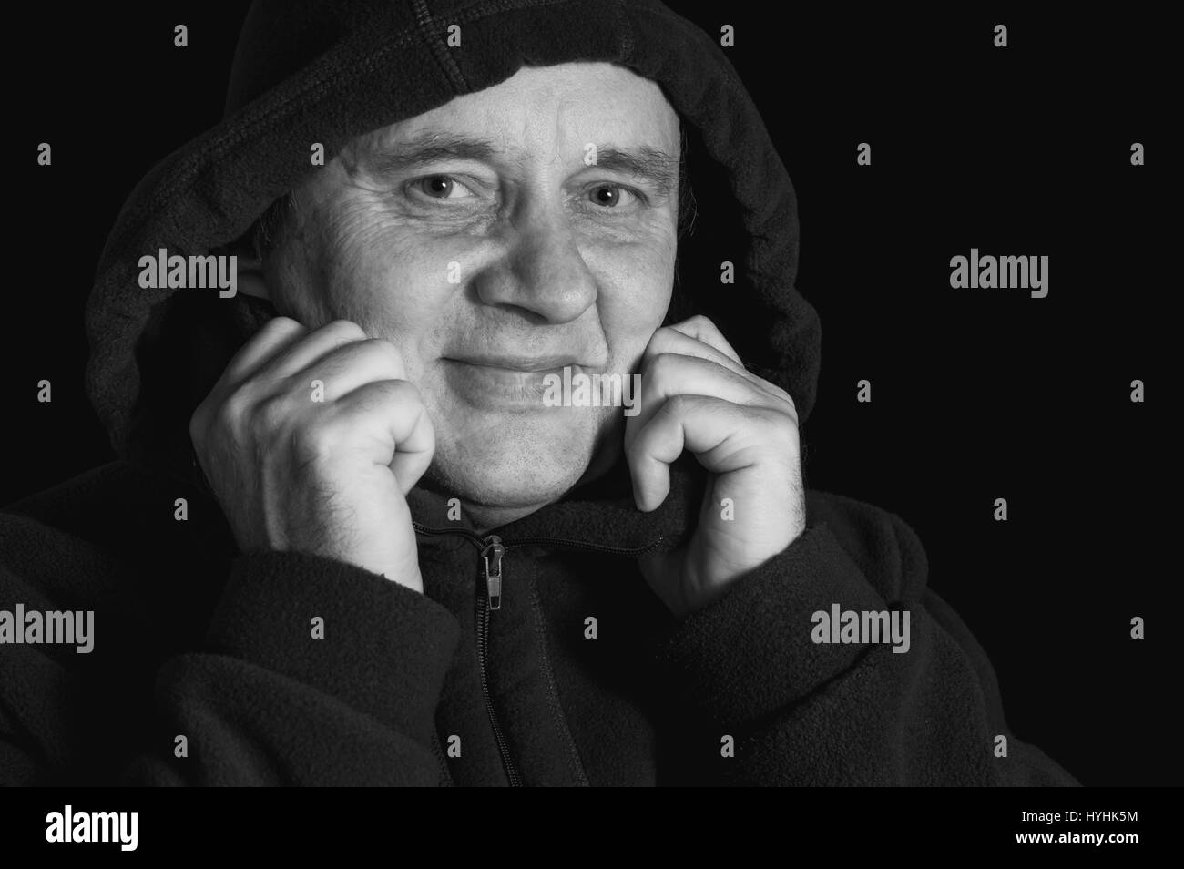 Nice black and white portrait of Caucasian smiling mature man wrapping himself in a coat Stock Photo
