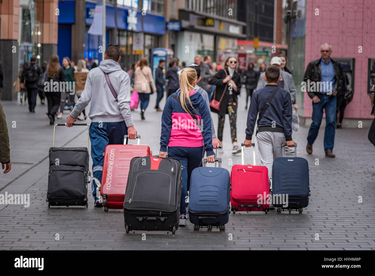 A family pulling suitcases through the street. Stock Photo